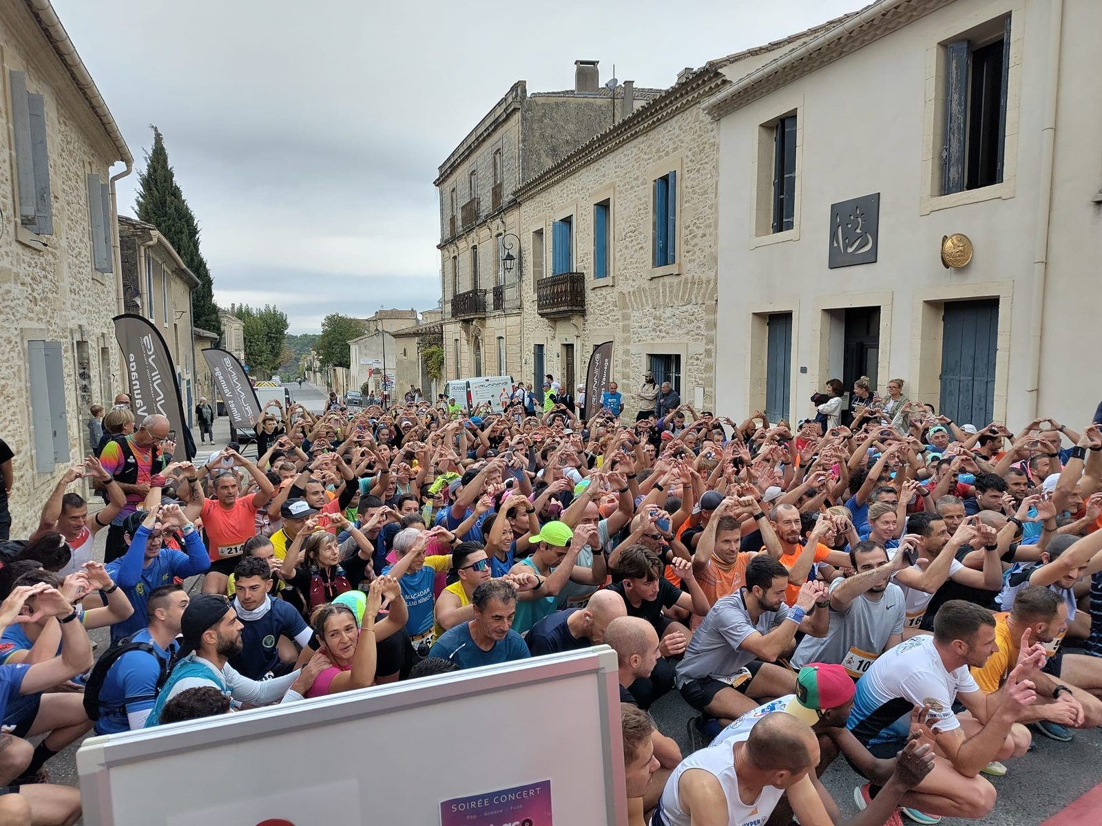 Des centaines de coureurs forment un cœur avec leurs mains juste avant le départ.